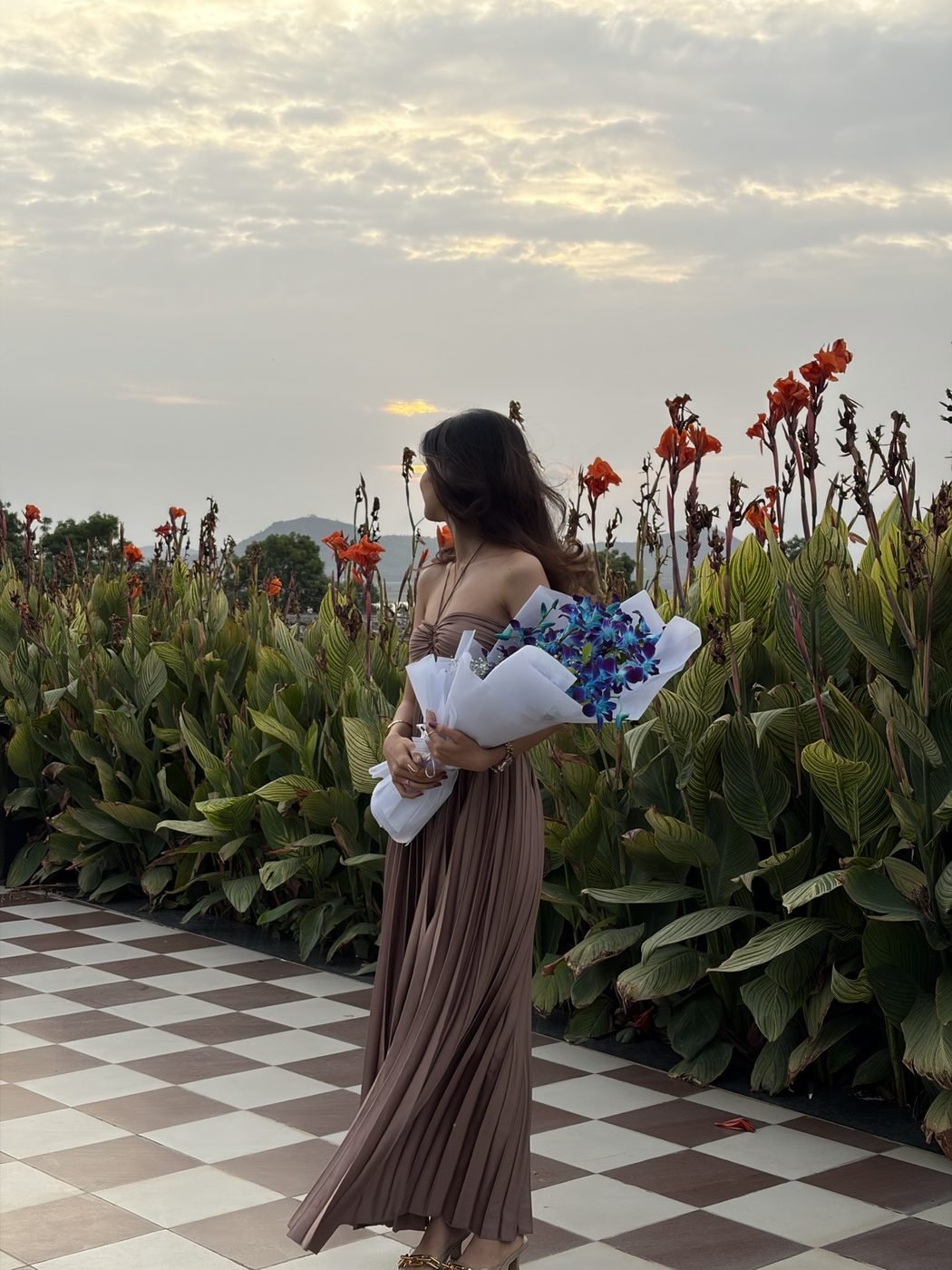 Disha Rokde holding a bouquet at golden hour on a rooftop