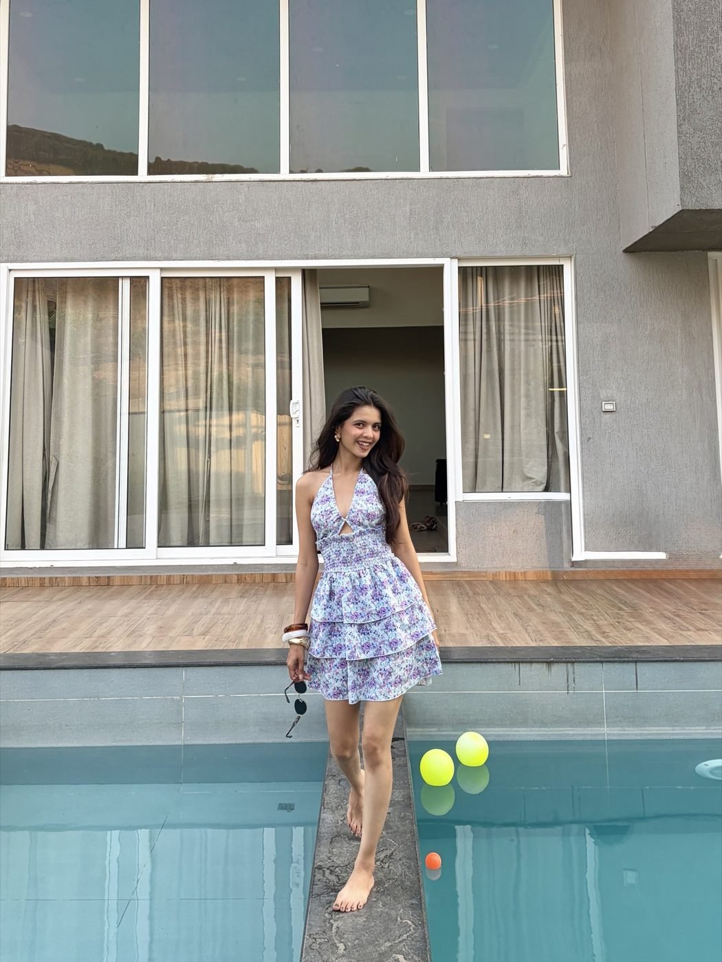 Disha Rokde in a printed mini dress beside a poolside villa